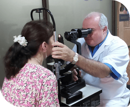 Doctor Dr. Iván Talero realizando un examen ocular a una paciente utilizando un biomicroscopio en una consulta oftalmológica.